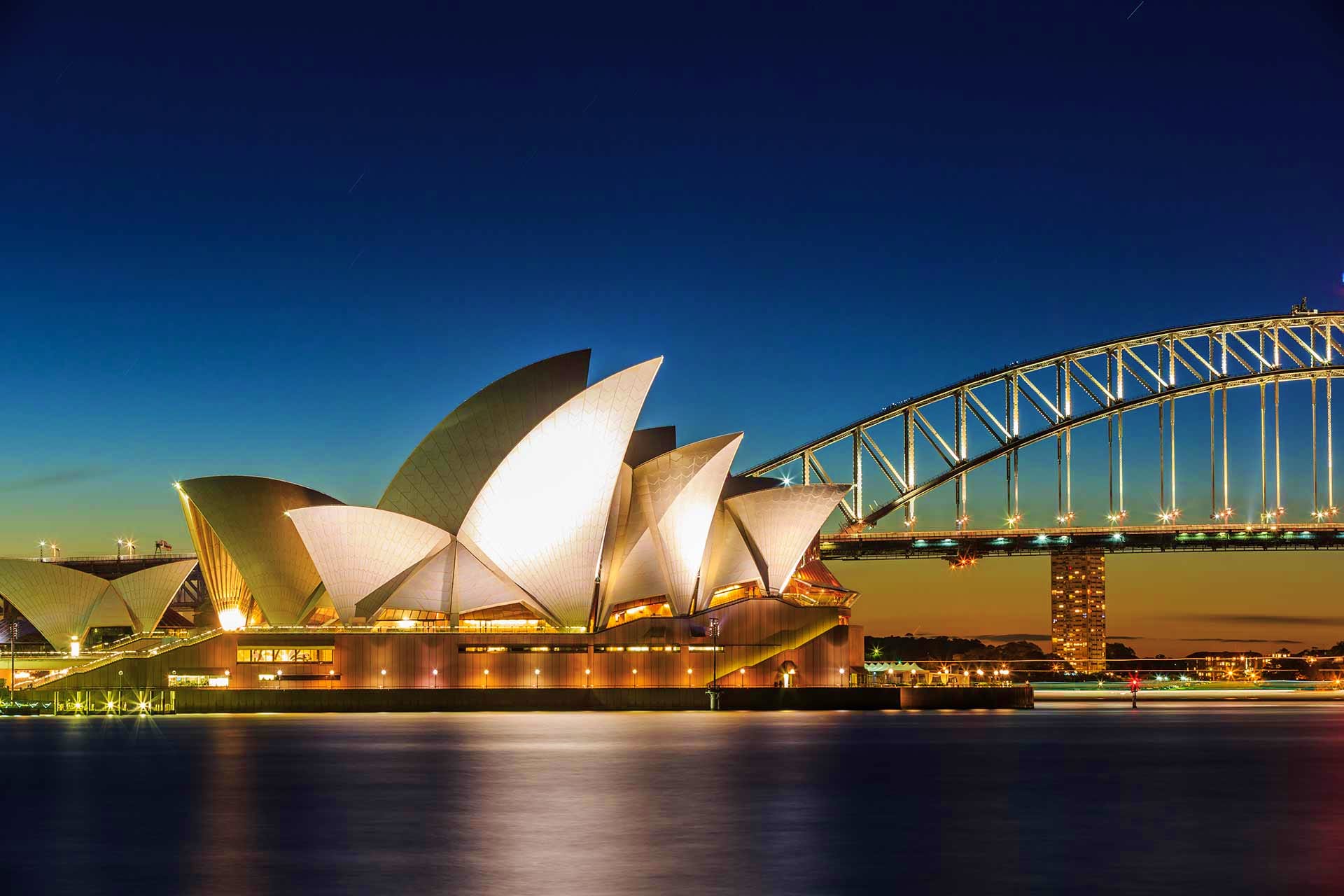 Sydney Opera House illuminated at dusk with Sydney Harbour Bridge in background, Australia